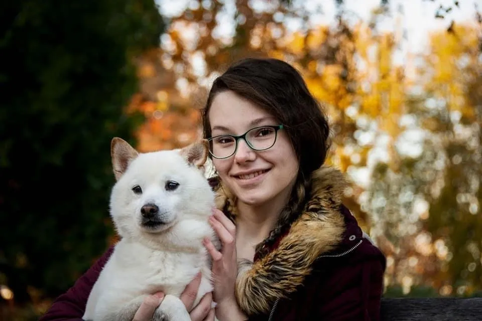 A woman holding her dog in the fall.