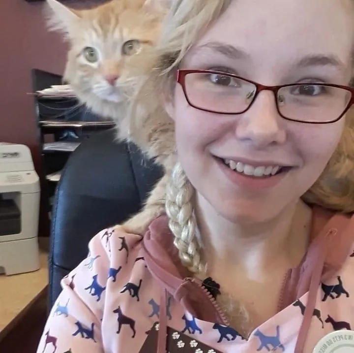 A girl with glasses and a pink shirt is smiling